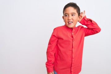 Sticker - Beautiful kid boy wearing elegant red shirt standing over isolated white background smiling with hand over ear listening an hearing to rumor or gossip. Deafness concept.