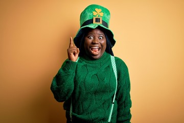 Sticker - Plus size african american woman with braids wearing green hat with clover on st patricks day pointing finger up with successful idea. Exited and happy. Number one.