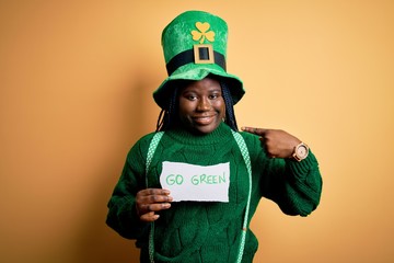 Sticker - Plus size african american woman wearing green hat holding paper on saint patricks day with surprise face pointing finger to himself