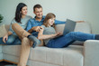© Space_Cat - Happy family using laptop at home: mom, dad and daughter shopping online or watching funny video or movie