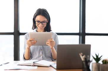 Wall Mural - Young girl holding tablet and using laptop