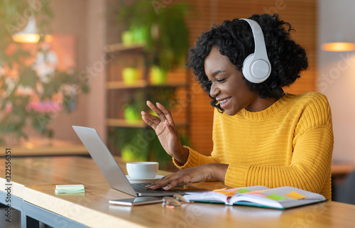 Fotomural Afro girl in headset using laptop, having skype conference