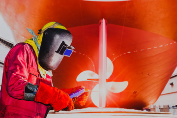 Ship repair industry Welding worker with spark light wear equipment protective on propeller with ludder background in shipyard.