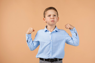 Wall Mural - little boy shows his biceps on beige background. child showing his muscles