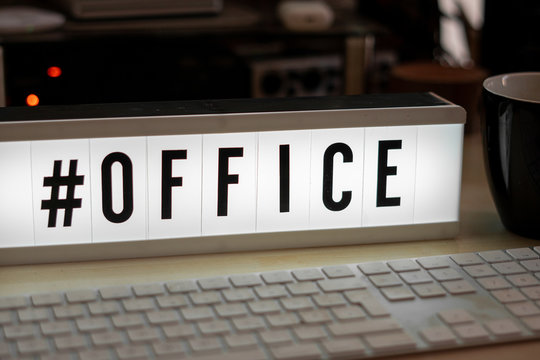 on a white illuminated cinema sign stands with black letters #office