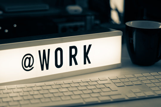  a white illuminated cinema sign with black letters @WORK