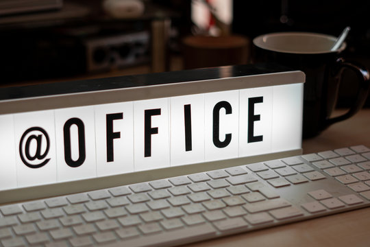 a white illuminated cinema sign stands with black letters @office