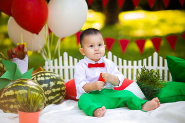 Laughing baby boy 1-2 year old eating watermelon outdoors. Summer party concept