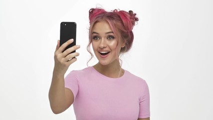 Canvas Print - A positive smiling young woman with the colored pink hairstyle is having a video call over white background