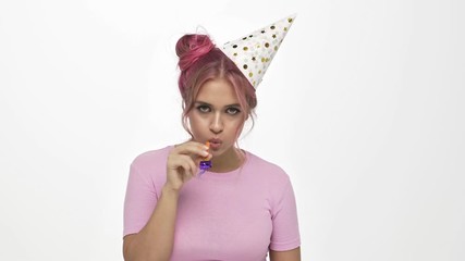 Sticker - A young woman with a boring face wearing a holiday hat is blowing a pipe over white background