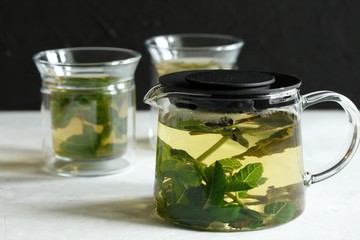 Wall Mural - Two glass cups with green tea with mint on a light gray table