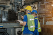 © alis - Industrial engineers in safety uniforms wearing yellow safety helmets are inspecting work by tools.  and on the job training he works in industrial machinery.