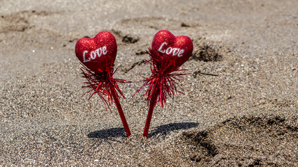 Two red hearts in the sand. Valentine's Day. Beach background