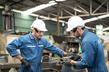 Industrial engineers in safety uniforms wearing white safety helmets are inspecting work by tools.  and on the job training he works in industrial machinery.