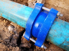 Blue Metal Plumbing Pipe Fittings, Gibault, For Connecting The Main Water Pipes That Require High Water Pressure. On The Ground Background. Water Supply System Maintenance. Selective Focus