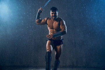 Muscular wet shirtless gladiator attacking.