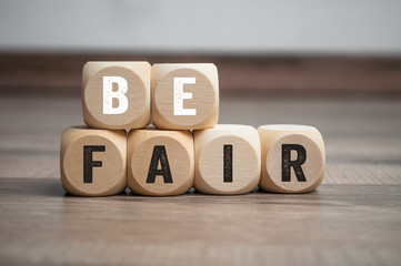 Cubes and dice with message Be fair on wooden background