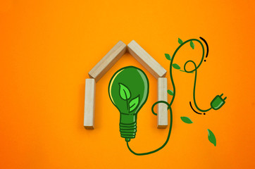 Eco save energy ecology green light blub drawing house made wooden blocks on the orange background