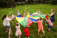Happy Kids Waving Rainbow Parachute Full Of Balls