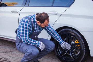 Tyre service worker cheking on a car wheel