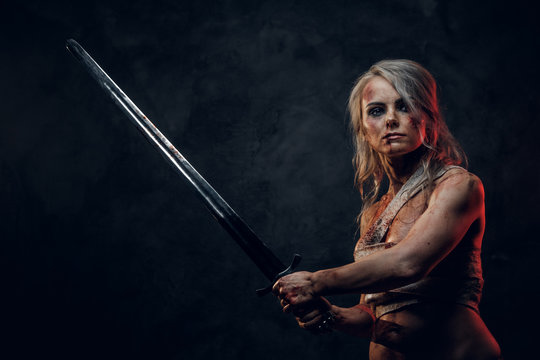Naked Fantasy woman warrior wearing rag cloth stained with blood and mud in the heat of battle. Studio photography on a dark background. Cosplayer as Ciri from The Witcher