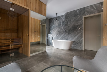 Luxurious bathroom with a snow-white bathtub against a marble wall in natural light