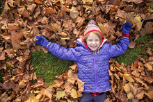 Little Girl Playing In The Leaves In A Park In Vienna, Austria.