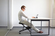 © endostock - Young man seating on kneeling chair and working with tablet in his office,   Stting posture at work