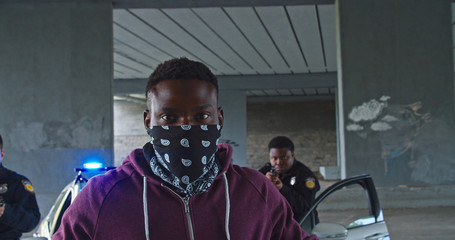 portrait of african american man thief with raised hands in front of policemen. two professional cops police officers arresting a dangerous offender in the city.