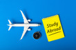 STUDY ABROAD - message on blue background with airplane model. Learning a language and studying abroad