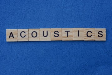 gray word acoustics from small wooden letters on a blue table