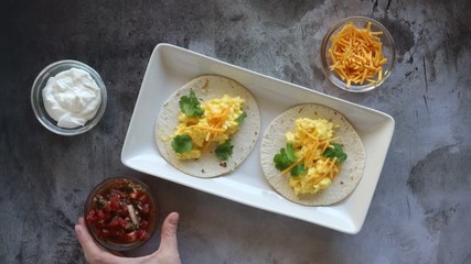 Wall Mural - Adding Salsa to Breakfast Tacos with Egg and Cheese