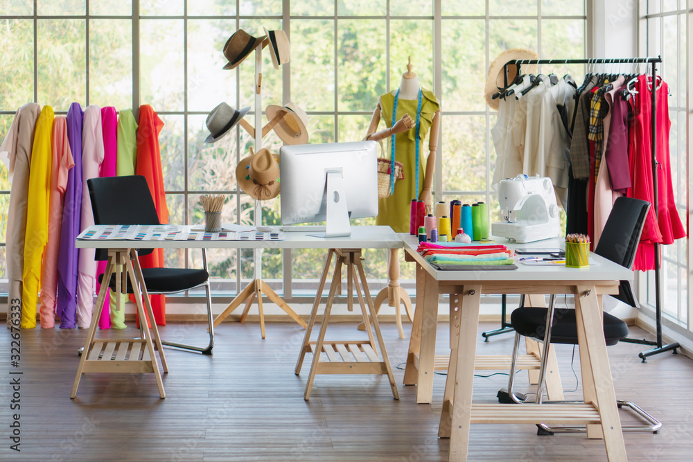 interior of dressmaker shop with dressmaking working desk and hanging rack with dress
