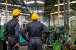 © narong - Soft blur image of the back of two technician men stand and look to various type of machine in factory.
