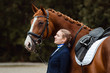Reiterin steht auf einem Turnier an der Schulter ihres Pferdes