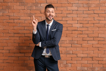 Wall Mural - Businessman with raised index finger on brick background. Concept of choice