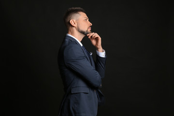 Thoughtful businessman on dark background. Concept of choice