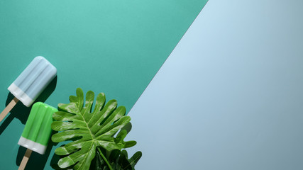 Overhead shot of lime and blue raspberry flavour popsicles on flat lay green and  blue background