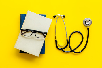 Wall Mural - Medical books near stethoscope on yellow background top-down