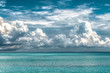 Calm ocean of turquoise color water and above it are huge dramatic cloud of type Cumulus during the onset of rainy season of monsoons; depicting the evaporation phase of Water cycle. Dream destination