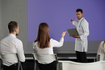 Canvas Print - Male doctor with laptop giving lecture in conference room with projection screen