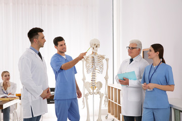 Wall Mural - Medical students and professor studying human skeleton anatomy in classroom