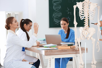 Wall Mural - Medical students studying human skeleton anatomy in classroom