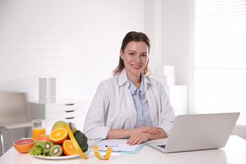 Wall Mural - Nutritionist with clipboard and laptop at desk in office