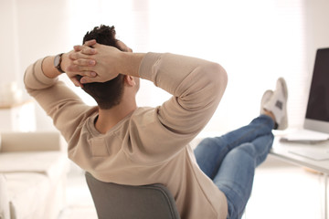 Wall Mural - Young man relaxing at table in office during break