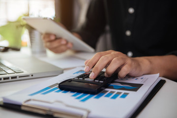 Businessman or accountant working on laptop computer with business document, graph diagram and calculator on office table in office.