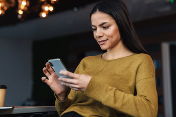 Wall Mural - Image of young businesswoman using cellphone while working in office