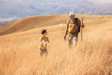 Wall Mural - Senior man with grandson on country walk in autumn.