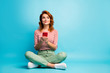 © deagreez - Full length photo of inspired dreamy woman sit floor legs crossed look copyspace use smartphone think want type blog post wear white stylish clothing shoes isolated blue color background