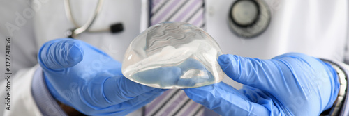 Fotografía Male doctor hand in blue protective gloves hold new fashion silicone breast implant closeup